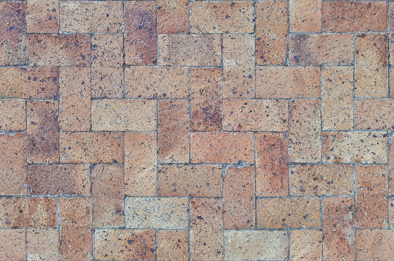 hero-img-01 Close-up of textured brick paver pattern in a herringbone layout.